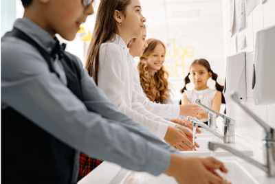 A boy and girls washing their hands under sinks
